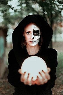 Witch wearing skull face paint and holding a moon light